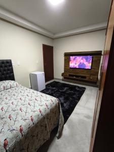 a bedroom with a bed and a flat screen tv at Lar Doce Lar Realizando Sono!!! in Arcos