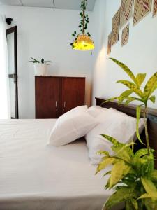 a bedroom with a bed with white sheets and a plant at Junction 14 Villa in Dikwella North
