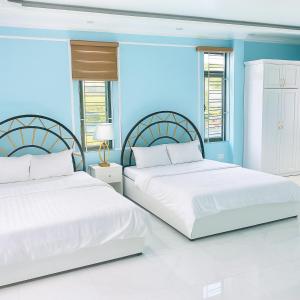 two beds in a room with blue walls and windows at King Hotel Hải Phòng in Hai Phong
