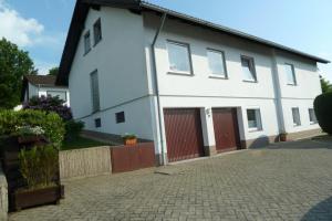 een wit huis met rode deuren en een oprit bij Ferienwohnung Casa Marlies In Daun in Daun