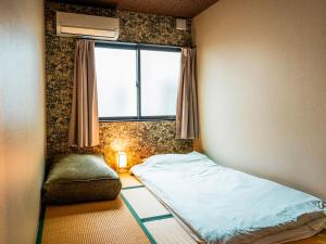 ein kleines Schlafzimmer mit einem Bett und einem Fenster in der Unterkunft -智 tomo- 難波 天王寺まで約15分 大阪観光に便利な和風宿 無料Wi-Fi in Osaka
