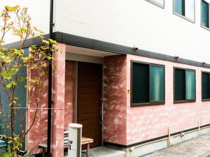 大阪市にある-智 tomo- 難波 天王寺まで約15分 大阪観光に便利な和風宿 無料Wi-Fiの木製のドアと窓のあるピンク色の建物