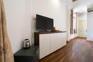 a living room with a flat screen tv on a cabinet at Rocky Hotel Ho Chi Minh in Ho Chi Minh City
