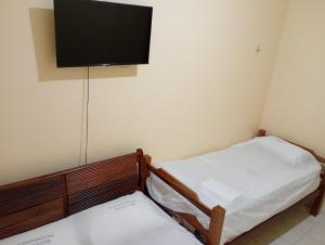 two beds in a room with a tv on the wall at Residencial Dom Luiz in Belém