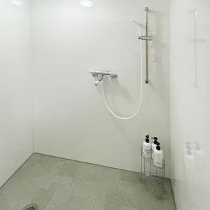 a white bathroom with a shower with three bottles at OLIVE Stay in Fukuoka