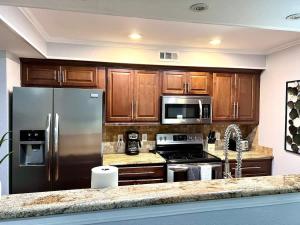 una cucina con elettrodomestici in acciaio inossidabile e mobili in legno di Spacious 2BD Condo Grand Prairie GP22B a Heliport-Facility 5A