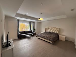 a bedroom with a bed and a couch and a tv at Cozy Suite in Brand New Luxury Home in Toronto