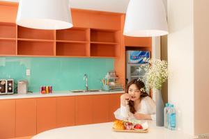 a woman sitting in a kitchen with a plate of fruit at Bazan Dalat Hotel in Da Lat