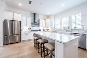 a kitchen with white cabinets and a large island with bar stools at Happily Eva After at Prominence 30A in Inlet Beach