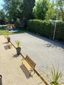 two park benches in a courtyard with plants at ZEcamping 4 étoiles pet friendly piscine et pétanque au cœur des Alpilles in Noves +51 photos