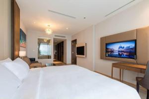 a bedroom with a large white bed and a flat screen tv at Panorama Sky Beach Recidences in Nha Trang