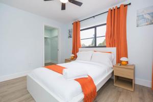a white bedroom with orange curtains and a bed at Clearwater Bliss Apartment 3 in Clearwater Beach +23 photos