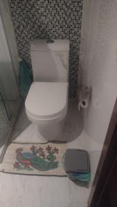a bathroom with a white toilet and a rug at martinshouse in Cabo Frio