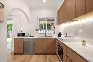 Una cocina con gabinetes de madera y un fregadero. en Inviting Single Room with Sunlit Comfort - Matraville - Shared Bathroom and Kitchen, en Sídney