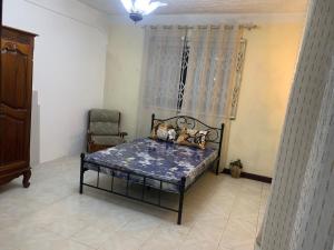 a bedroom with a bed in a room with a chair at FINRAH Rental Property Ltd in Curepipe
