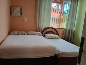 two twin beds in a room with a window at Casa Mosqueiro in Belém