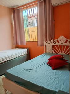 a bedroom with a bed with a red pillow on it at Casa Mosqueiro in Belém