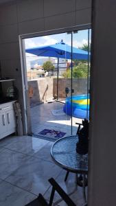 an open door to a patio with a table and an umbrella at Apto Perequê Sacada Frente in Porto Belo