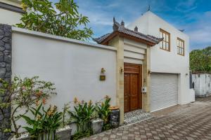 チャングーにあるVilla Casa Adelineの茶色の扉と植物のある白い家