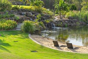 un jardin avec un étang et deux chaises sur la pelouse dans l'établissement King Bed w Ensuite - Sleeps 8 - Lake Aquascape, à Neranwood