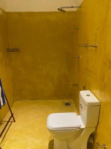 une salle de bain avec des toilettes blanches et un mur jaune dans l'établissement Costal View, à Ahangama