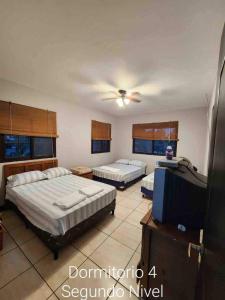 ein Schlafzimmer mit zwei Betten und einem Fernseher in der Unterkunft Villa Fluvia Rafaela in Retalhuleu