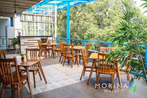 un restaurante con mesas de madera y sillas en el balcón en Sunrise Hotel Malang, en Rampal