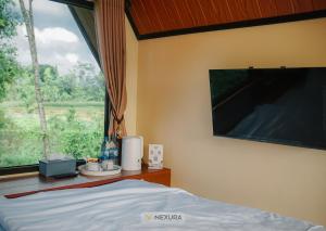 a bedroom with a bed and a large window at The Kotenang in Wonosobo