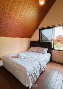 una cama en una habitación con una ventana grande en The Kotenang, en Wonosobo