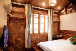 a bedroom with wooden walls and a bed and a tv at Huazhu Baihe Huagu Inn in Wang-ts'un
