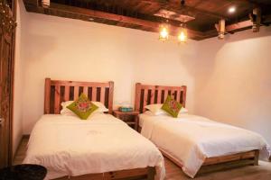 two beds in a room with white walls at Huazhu Baihe Huagu Inn in Wang-ts'un