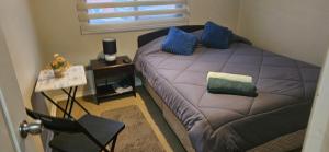 a bedroom with a bed with blue pillows on it at Buen descanso cómodo y acogedor en Machali con Parcking y WIFI in Machalí