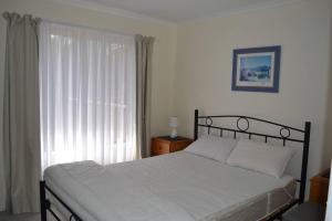 a bedroom with a bed with white sheets and a window at Lees171 in Evergreen