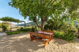 un banco de madera sentado en la arena bajo un árbol en Haus Gaia, en Rabac