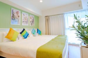 a bedroom with a large white bed with colorful pillows at Higashi-Shinjuku 906 in Tokyo