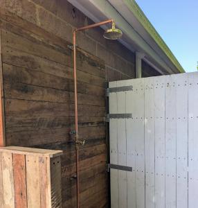 a shower in a building with a wooden wall at 10 min walk to beach & cafés with a quiet, private fenced garden in Byron Bay +3 photos