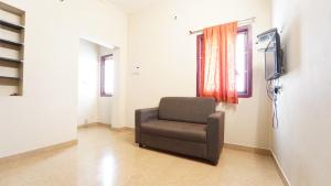 a chair sitting in a room with a television at Varun Residency New in Coimbatore +22 photos