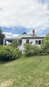 a white house with a green roof and a yard at Healesville Gardener's Cottage in Healesville