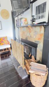 a living room with a fireplace and a stack of books at Healesville Gardener's Cottage in Healesville +15 photos