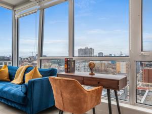 ein Wohnzimmer mit einem blauen Sofa und großen Fenstern in der Unterkunft VOGUE Suites Toronto Downtown - Entertainment District in Toronto