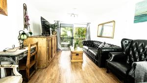 a living room with black leather furniture and a television at Loft Apartment - 1 Bedroom in Brunswick Heads +5 photos