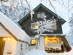 a house covered in snow with lights in the window at Pension Razteca in Hakuba