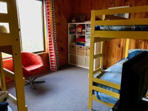 a bedroom with two bunk beds and a chair at Manna Gum Beach House in Evergreen