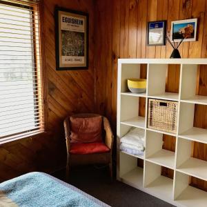 a bedroom with a book shelf and a chair at Manna Gum Beach House in Evergreen