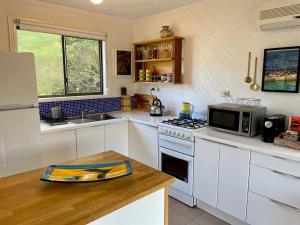 a kitchen with white cabinets and a stove top oven at Manna Gum Beach House in Evergreen +6 photos