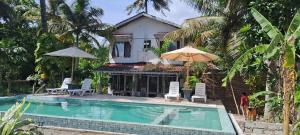 a villa with a swimming pool in front of a house at Simple Place in Mirissa