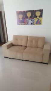 a brown couch in a living room with a painting at FLAT ACONCHEGANTE poucos min da praia in Maceió