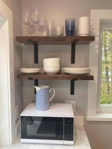 a microwave on a counter with plates and bowls at Lake Cabin Ideal for Outdoor Adventures in Maine in North Harpswell