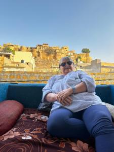 a woman sitting on a bed with a view at Mirvana Guest House & Camel safari in Jaisalmer +80 photos