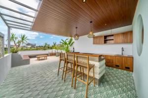 Tumbak Bayuh4Br Brand New Canggu Modern Villa的开放式厨房，配有木制橱柜和带椅子的吧台。